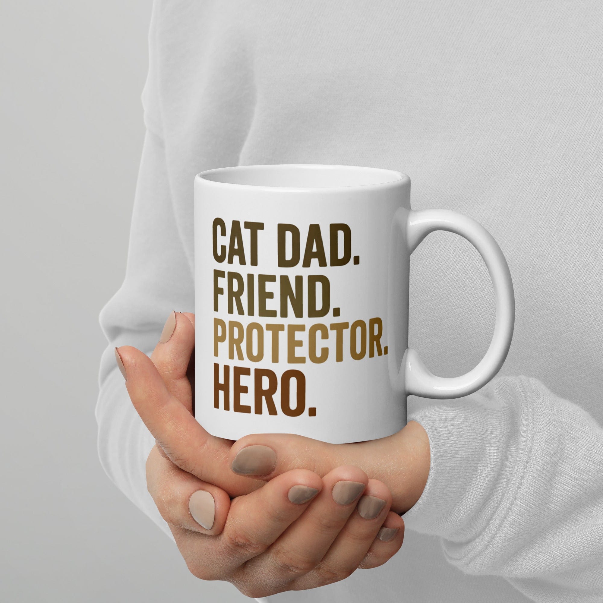 person holding white mug that says cat dad, friend, protector, hero
