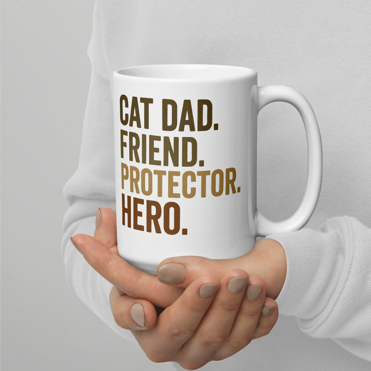 person holding white mug that says cat dad, friend, protector, hero