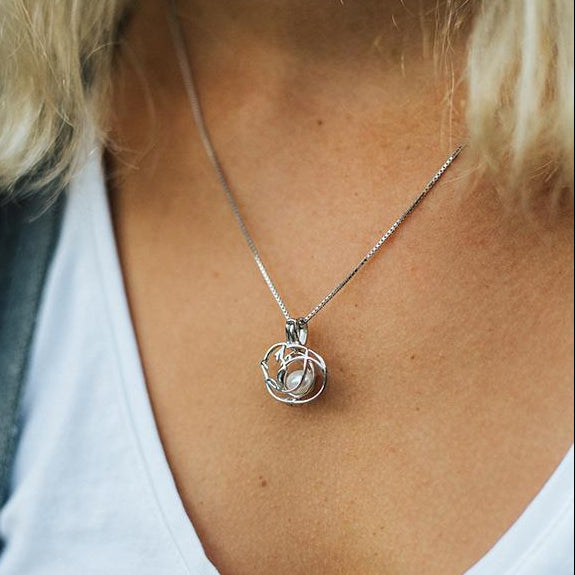 TripleTStudios original design Cat Nap Pearl Pendant on a sterling silver necklace modeled by a person with blonde hair in a blue shirt.